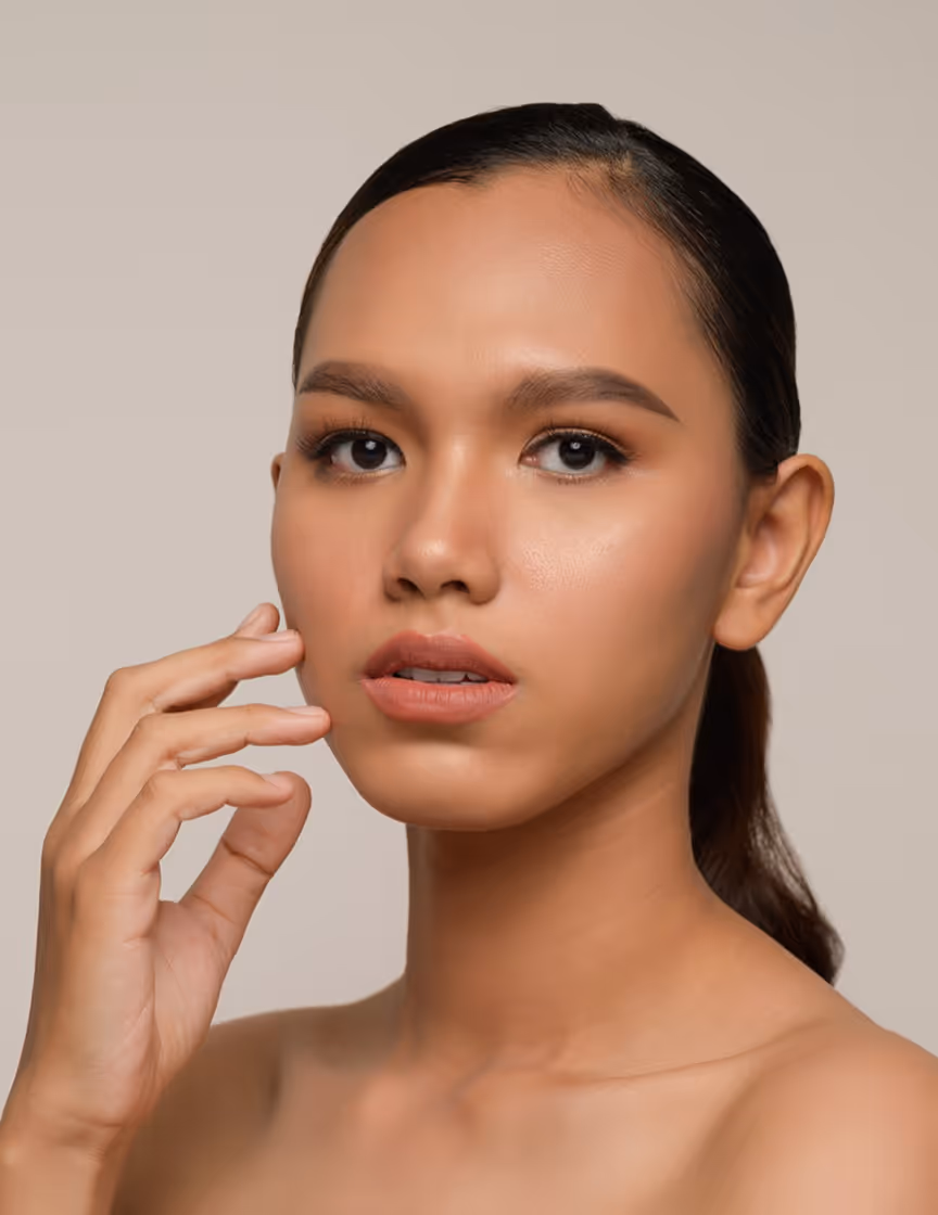 Portrait of a woman with smooth skin and natural makeup touching her face with her fingers.