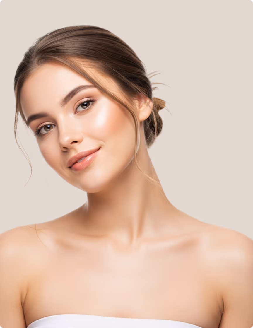Young woman with glowing skin and brown hair in a bun against a beige background.