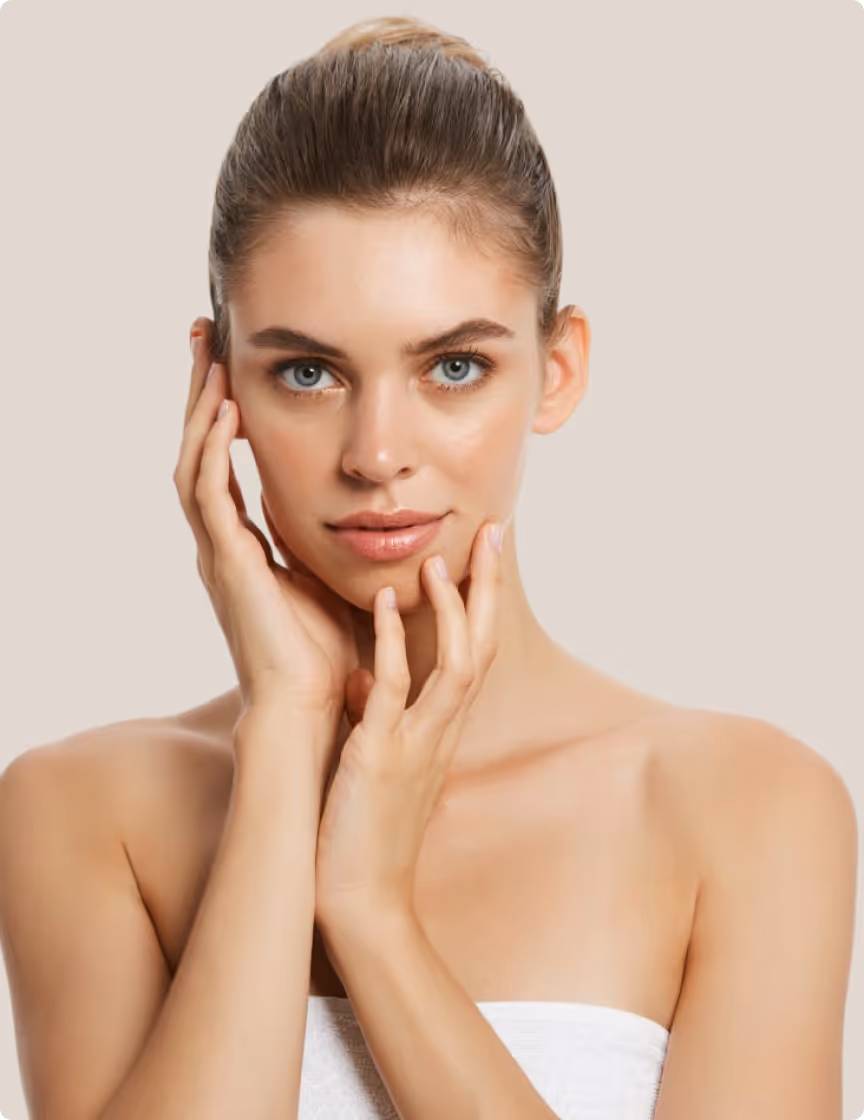 Young woman with clear skin gently touching her face against a plain beige background.