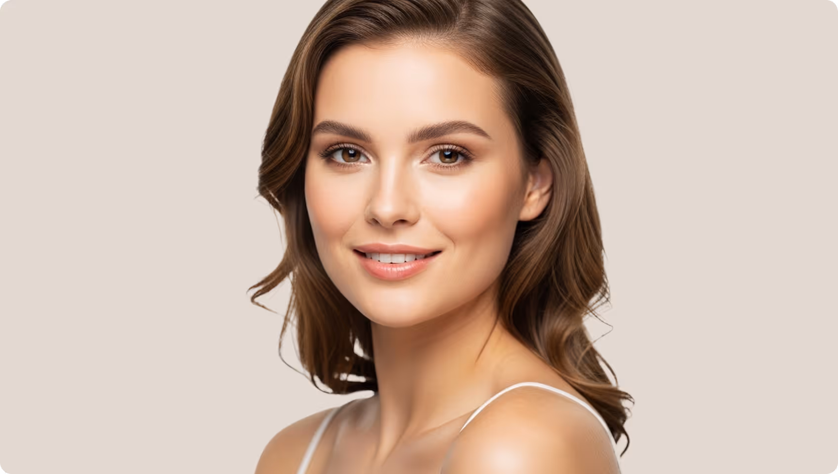 Portrait of a smiling young woman with clear skin posing with her hand near her chin.