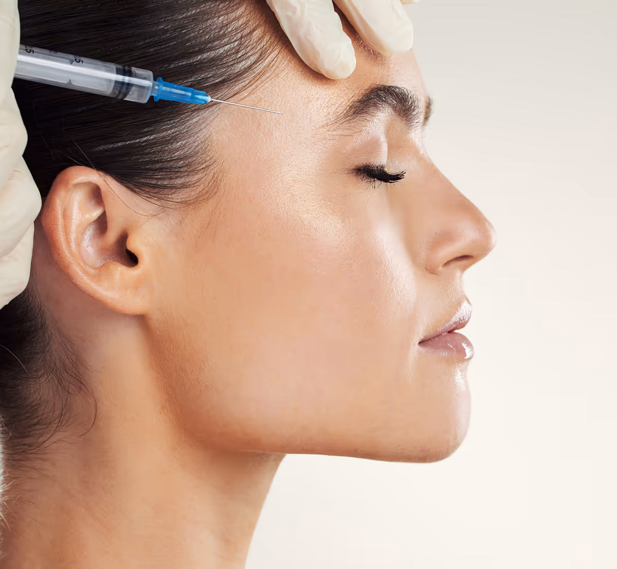Side profile of a woman receiving a cosmetic injection near her temple.