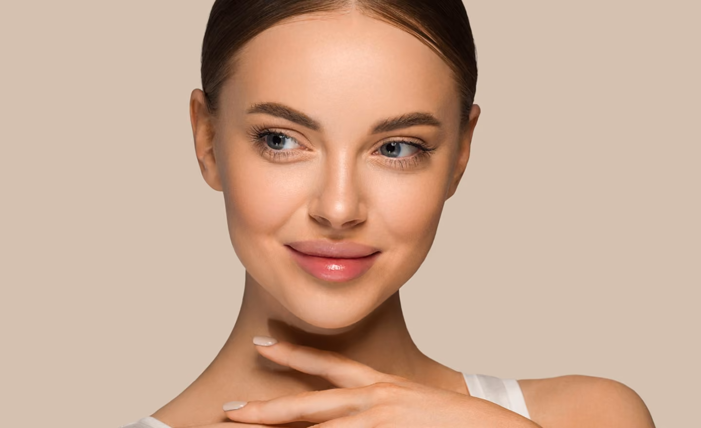 Close-up of a smiling woman with clear skin looking to the side and hand near her neck.