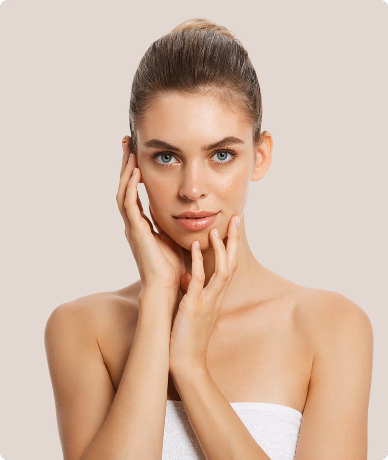 Portrait of a smiling young woman with clear skin posing with her hand near her chin.