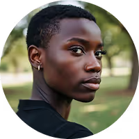 Close-up portrait of a young person with short hair and an earring looking over their shoulder outdoors.