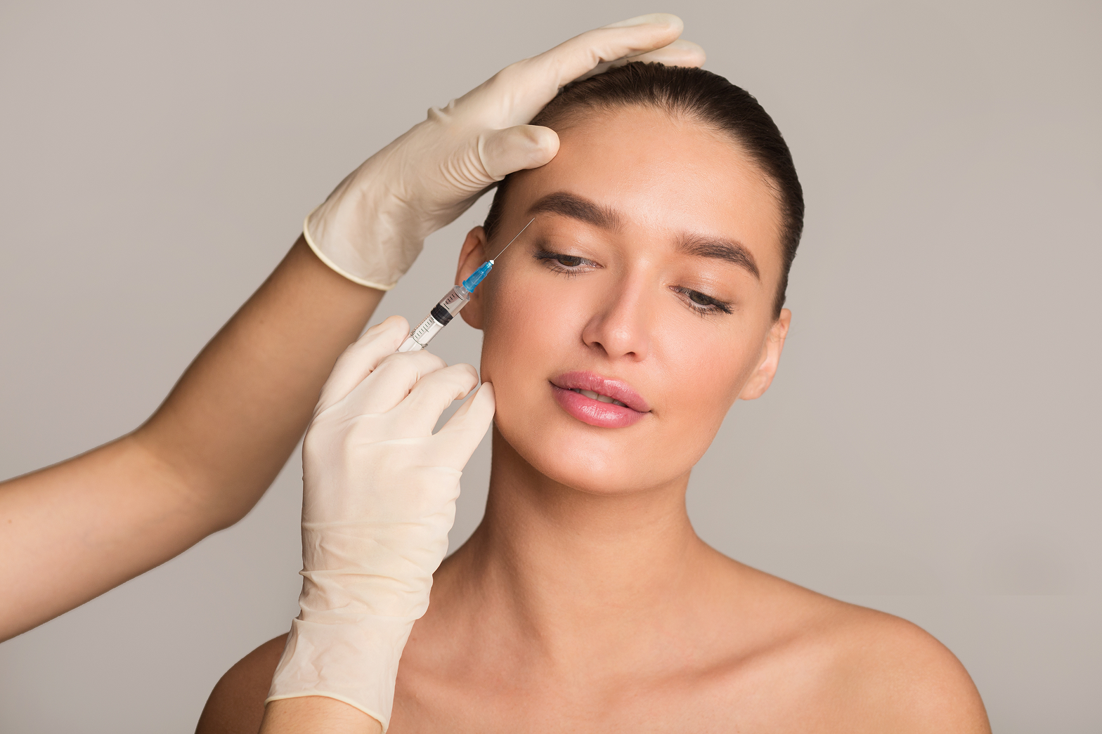 A woman getting her eyebrows done by a doctor.