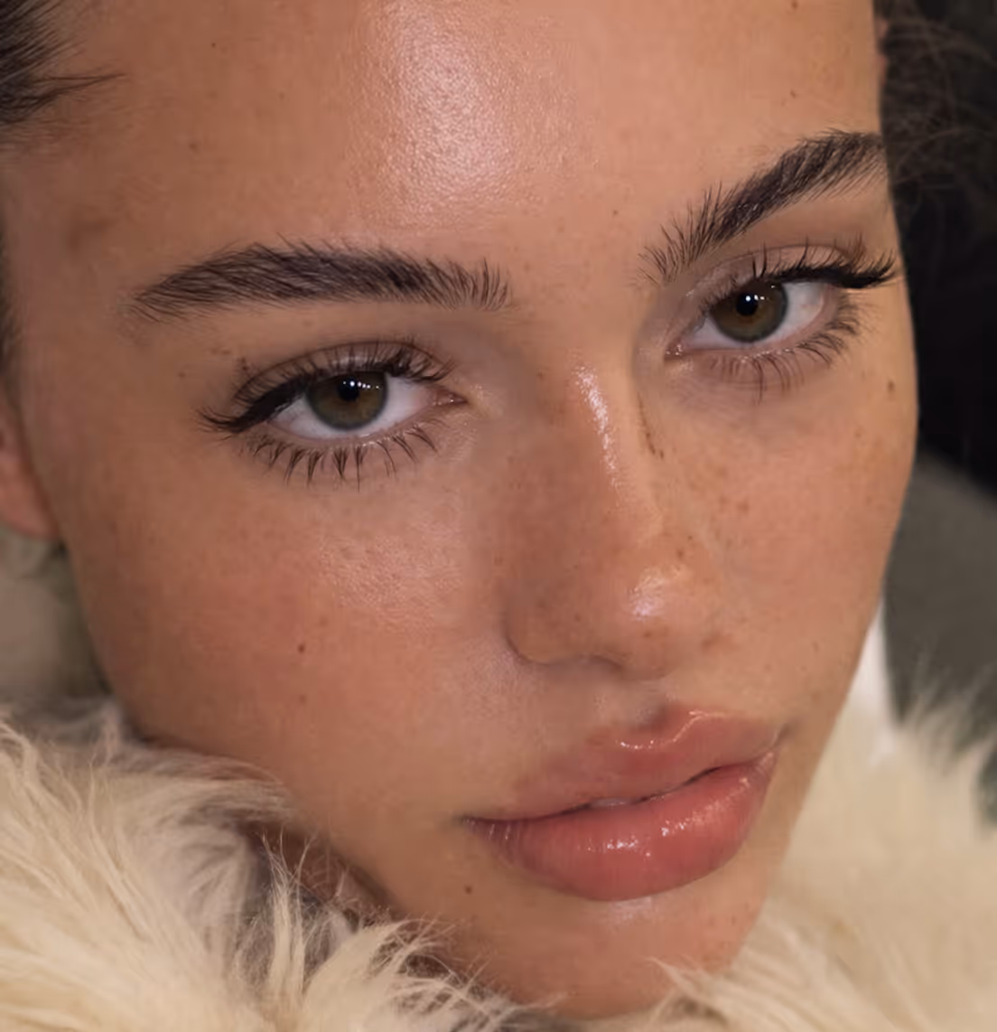 Portrait of woman with glossy skin and natural makeup, framed by soft fur for a refined beauty look