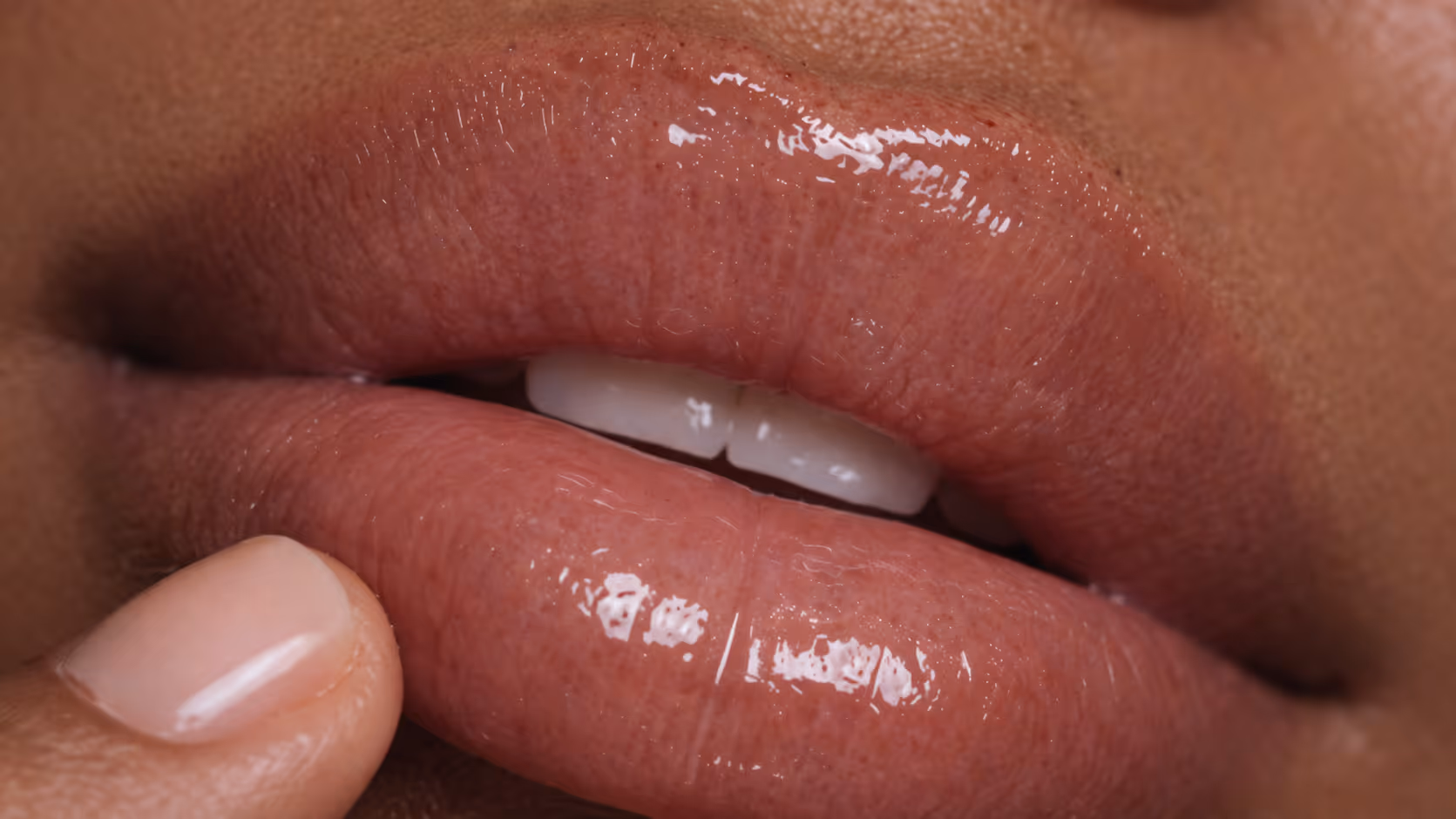 Close-up of lips with gloss and visible skin texture, highlighting hydration and natural finish