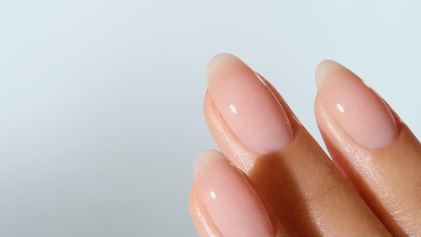 Close-up of hand with glossy nude manicure, showcasing smooth finish and clean nail shape
