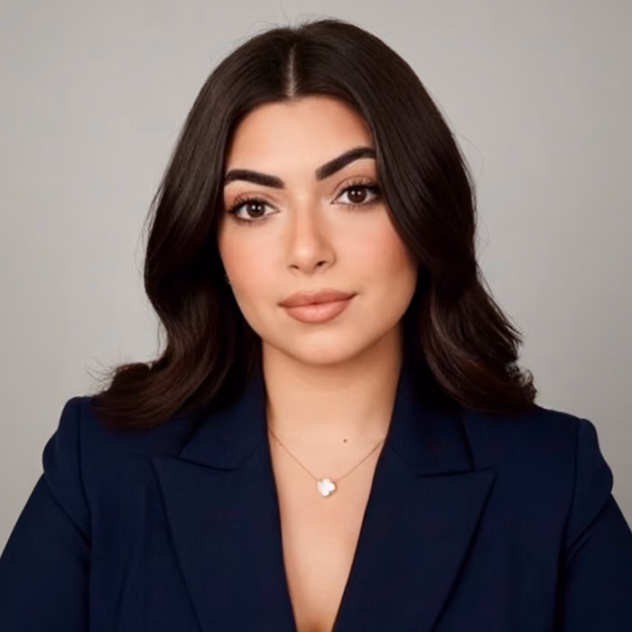 Rebecka Infante, headshot in a navy blazer against a gray backdrop.