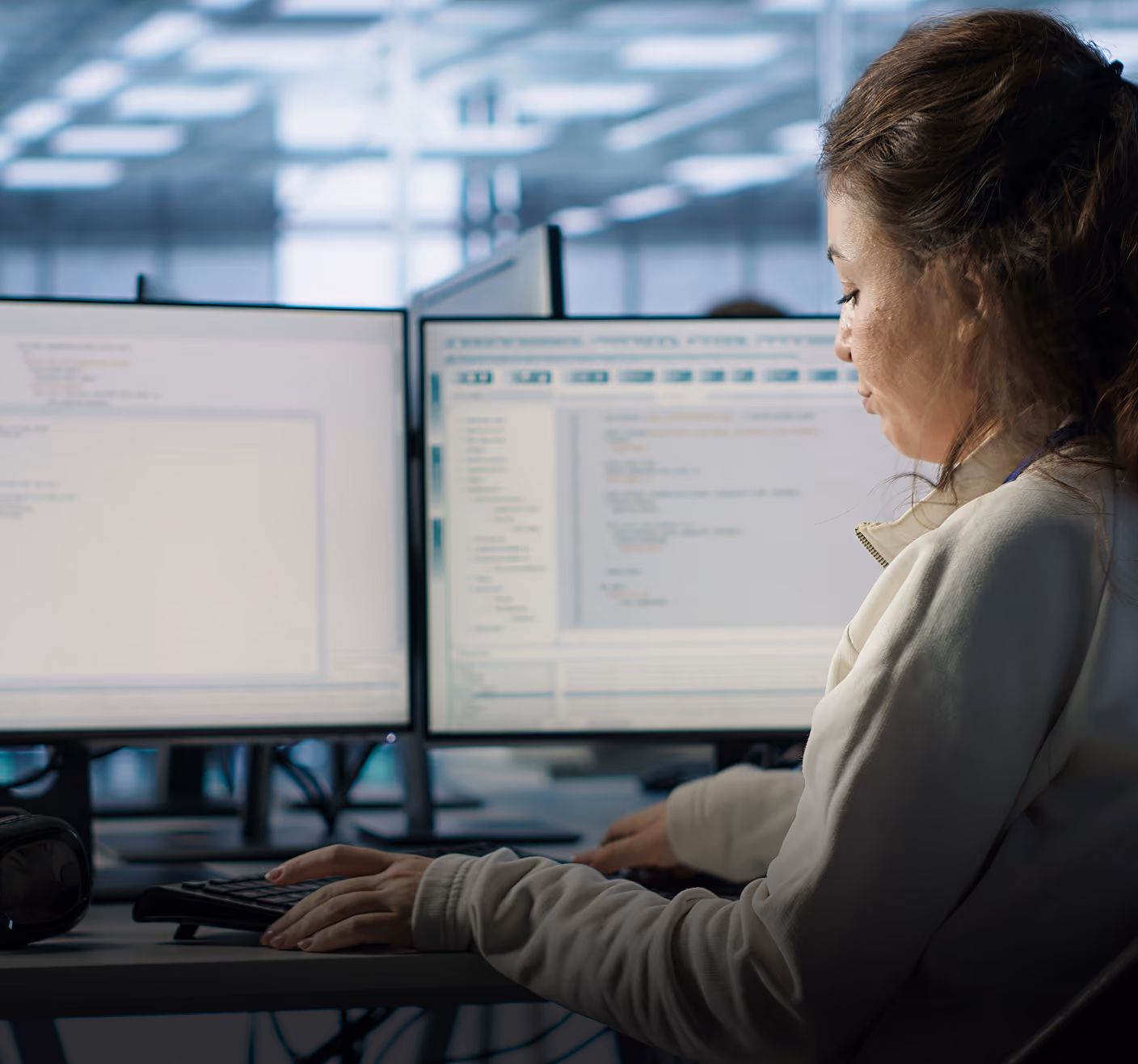 Engineer working on code across two monitors