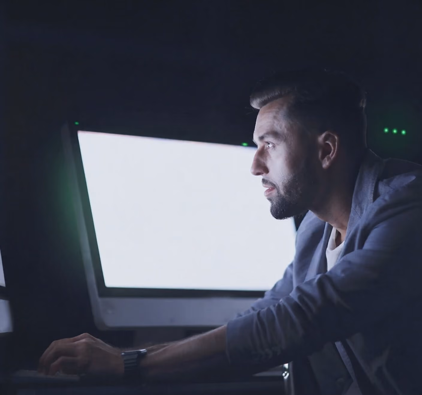 Security engineer monitoring systems in a dark control room