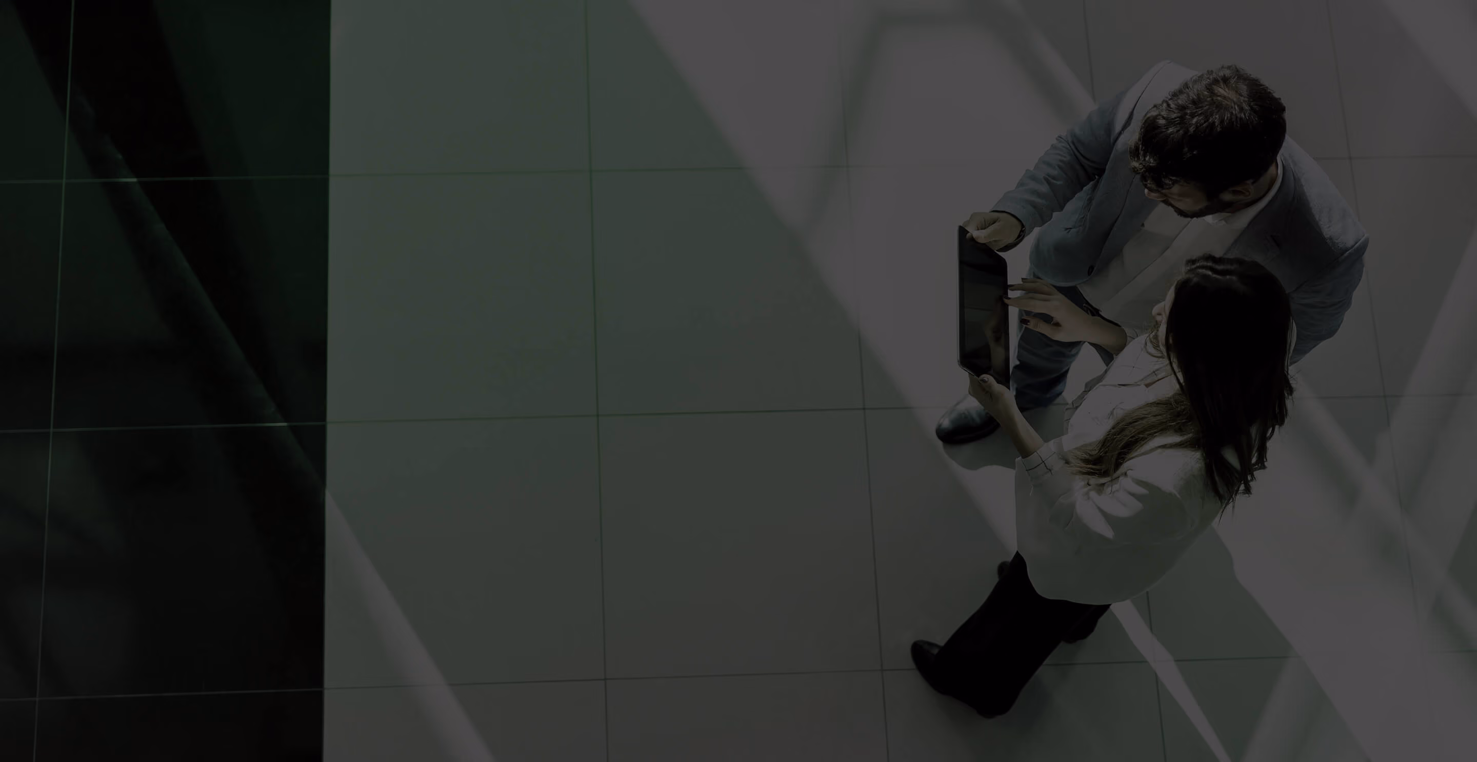 Two colleagues reviewing documents on a tablet, seen from above