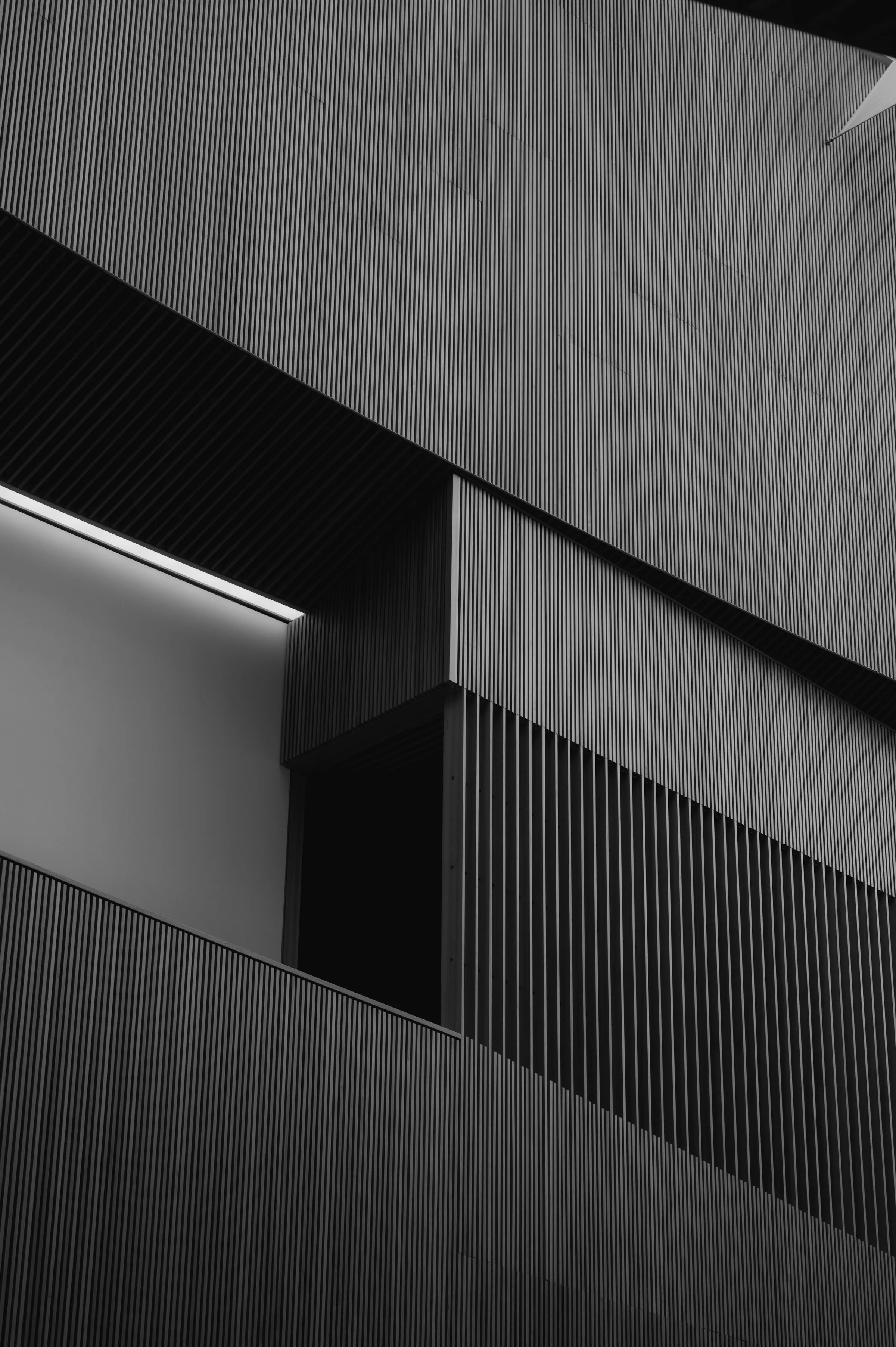 Black and white photo of a modern building exterior with vertical striped panels and geometric shapes.
