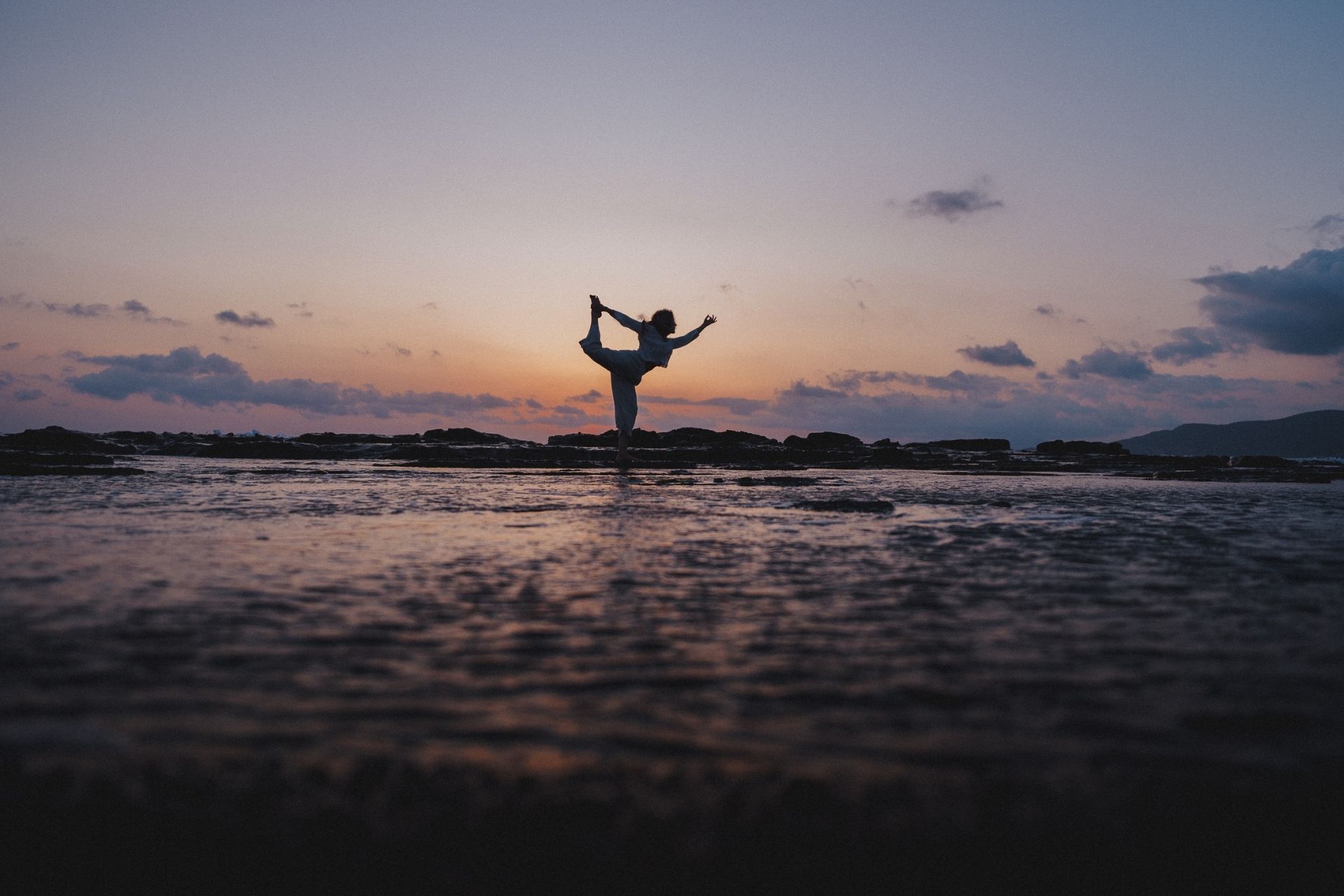 Michi in der Yoga Tänzer Pose am Strand, während des Sonnenuntergangs