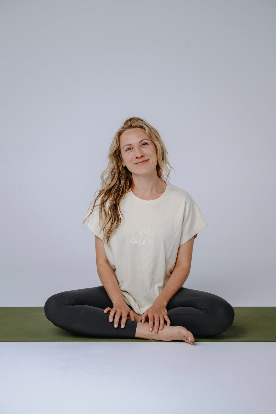 A photo of Michi sitting on a yoga mat in a studio.