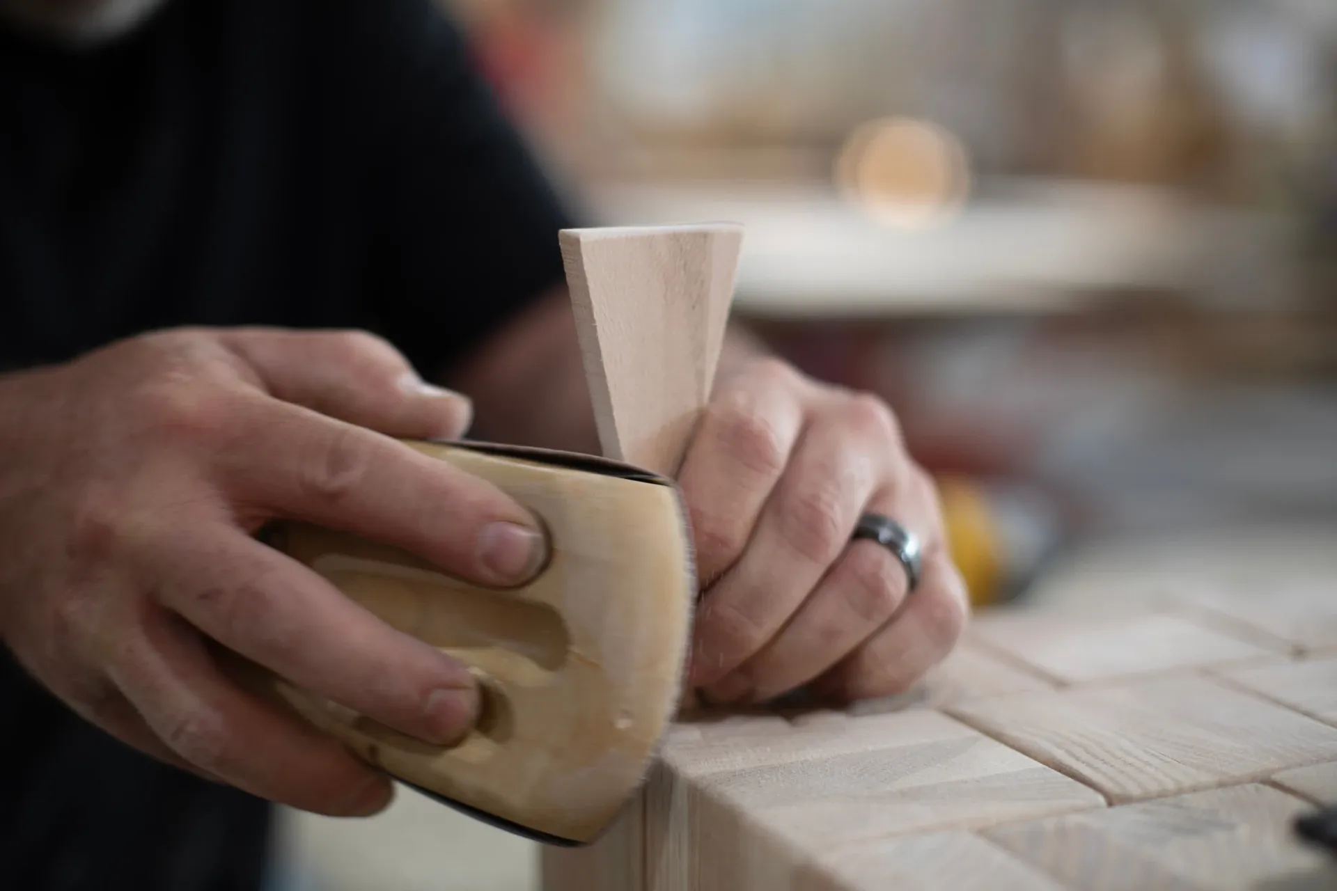 hands using a handheld sander on a piece of wood