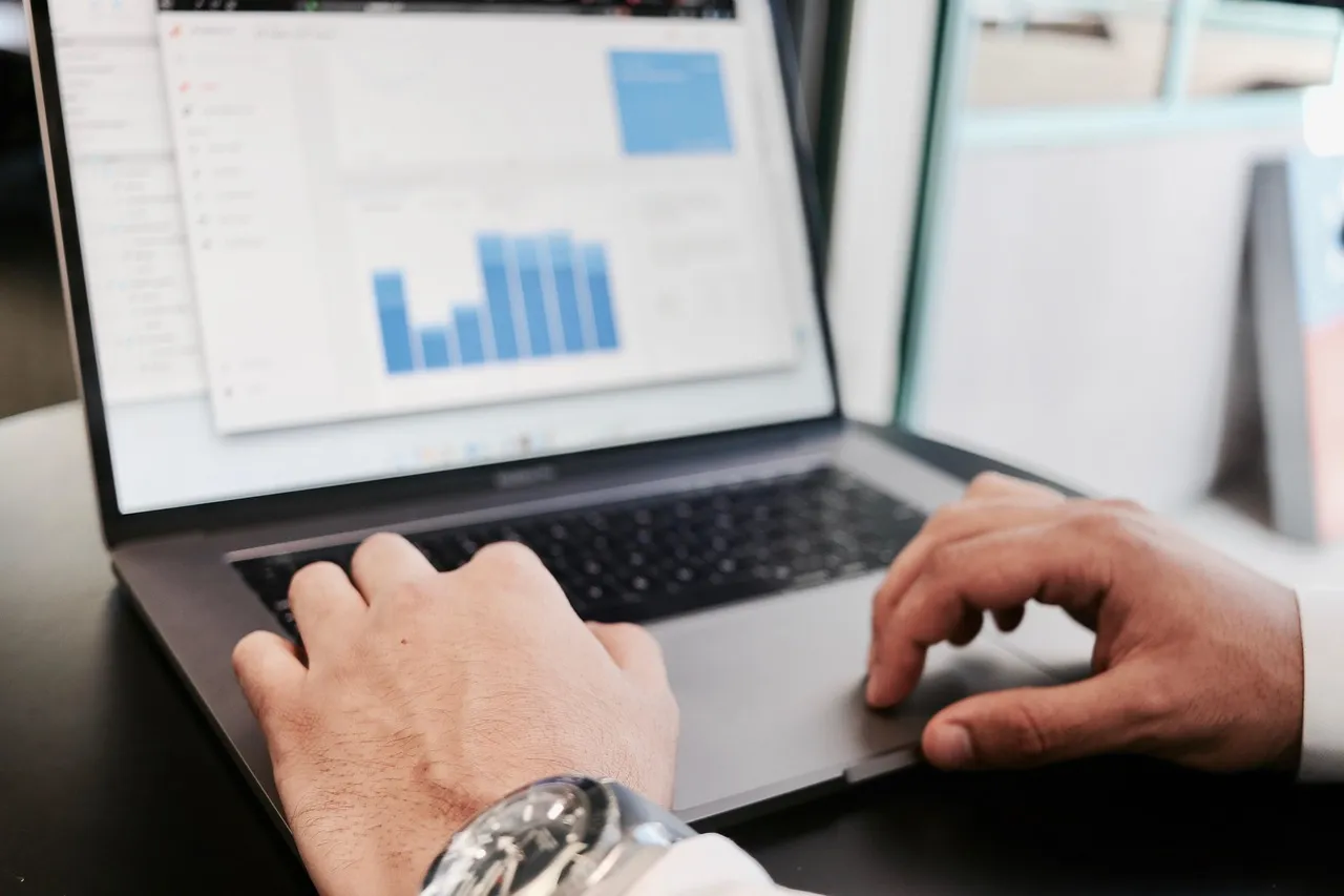 Close-up of hands typing on a laptop displaying data analytics charts, illustrating practical data handling and analysis skills taught in IT and AI (KI) training for digital commerce