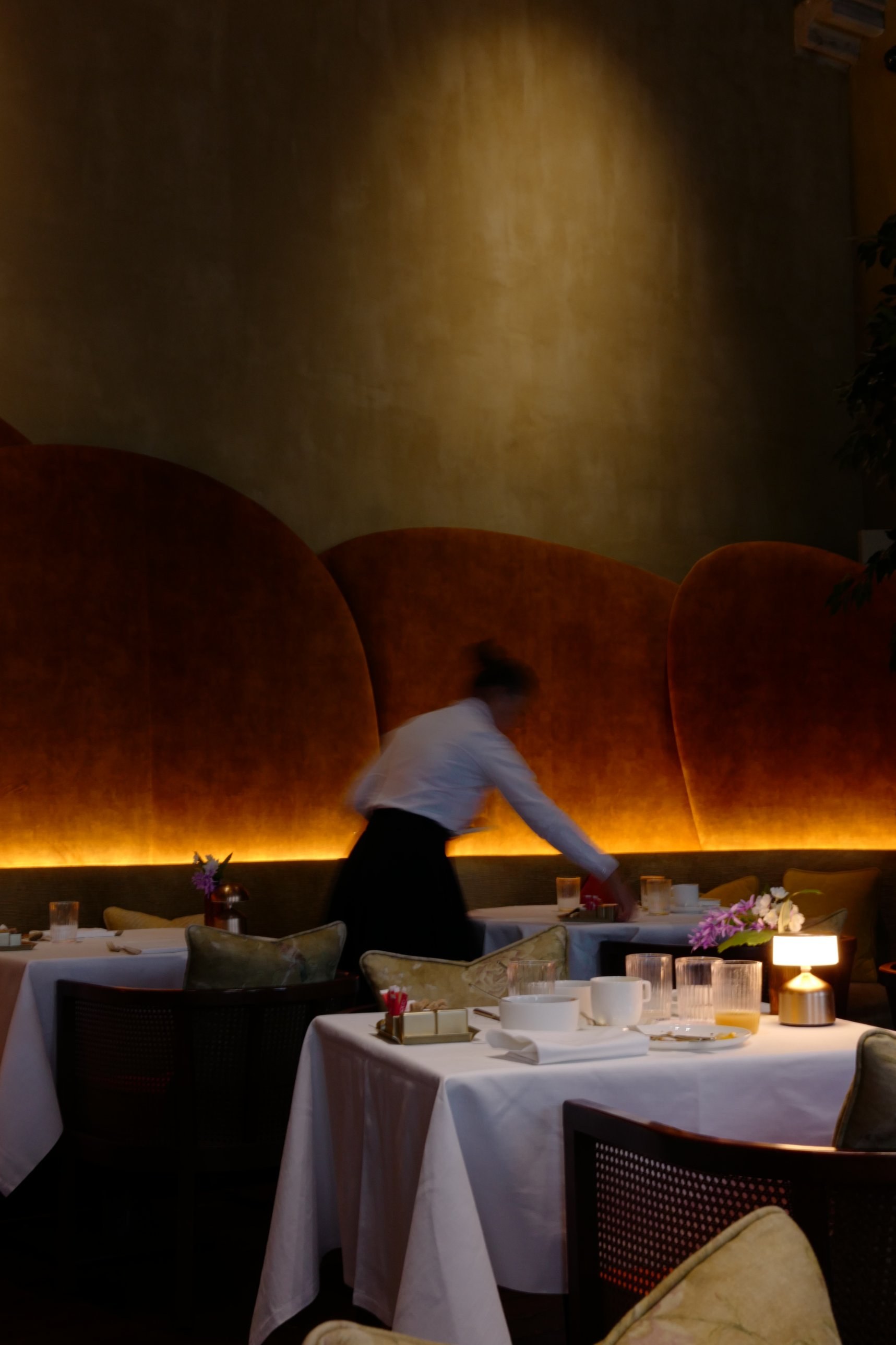 The breakfast hall, velvet banquettes beneath a high wall