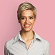 Smiling woman with short blonde hair wearing a striped button-up shirt against a pink background.