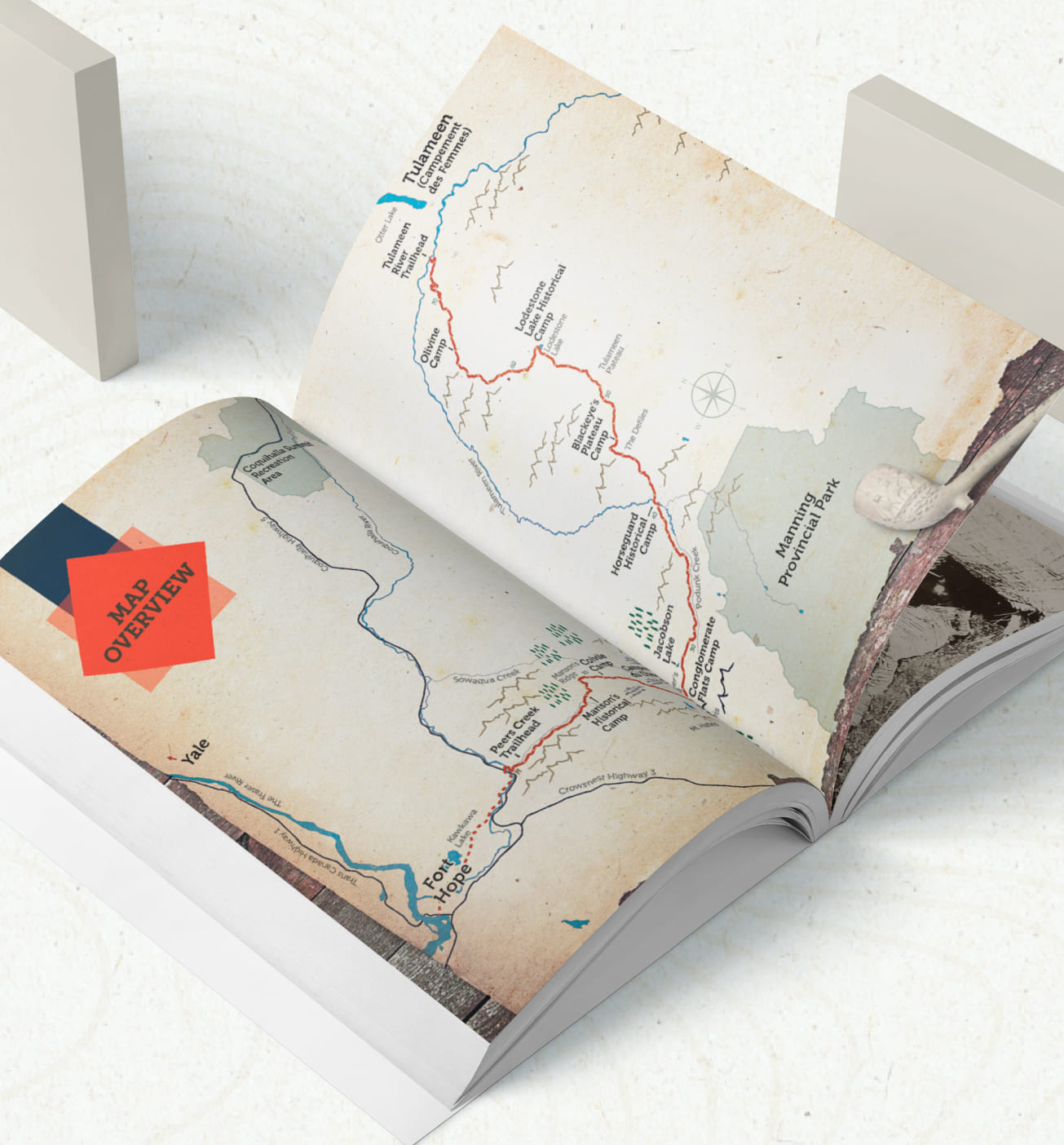 Open book displaying an illustrated map with hiking trails, landmarks, and geographic details on textured pages.