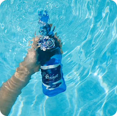 Mano sosteniendo una botella bajo el agua en una alberca turquesa