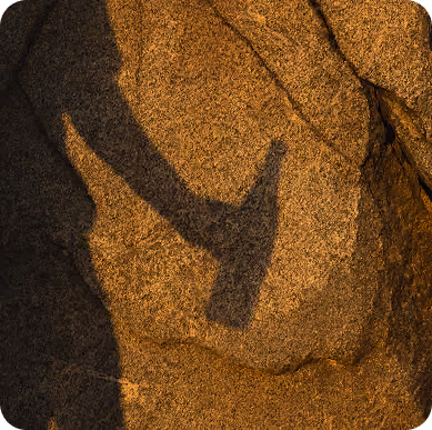 Sombra de una mano y una botella sobre roca dorada