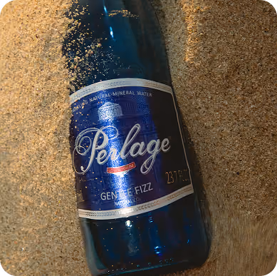 Lata de agua mineral Perlage sobre la arena