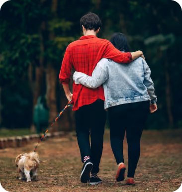 Pareja paseando a su perro tomados del brazo