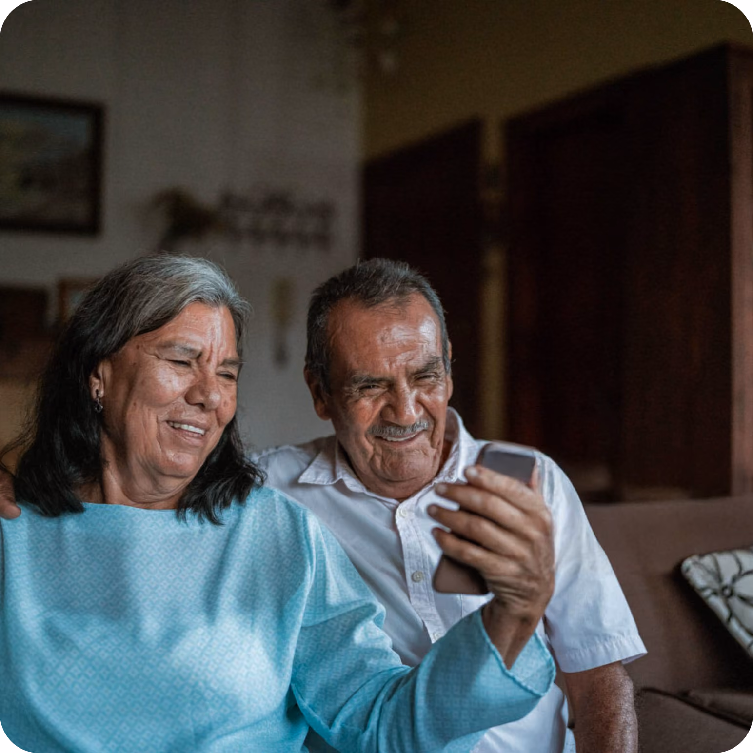 Pareja mayor sonriendo frente a un teléfono