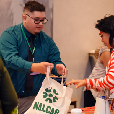 Handing out tote bags at the NALCAB booth