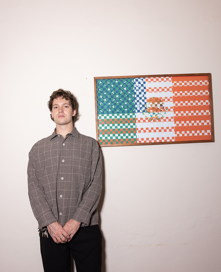 Wyatt Shomion, Estratega Creativo de Calo — retrato frente a una obra de banderas EUA–México
