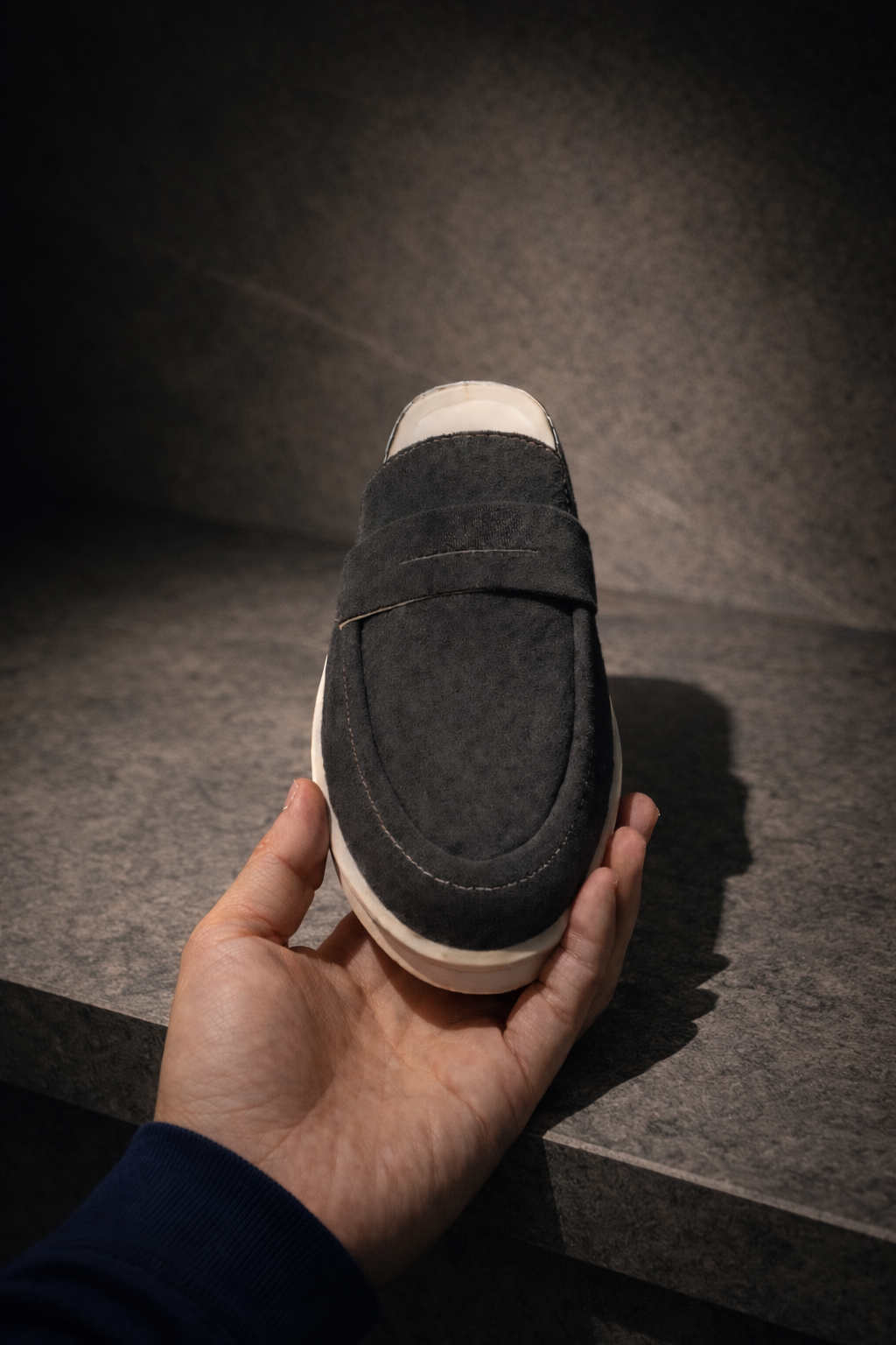 Person wearing dark suede KMRO mule slip-on shoes with cream rubber outsole in an urban setting.