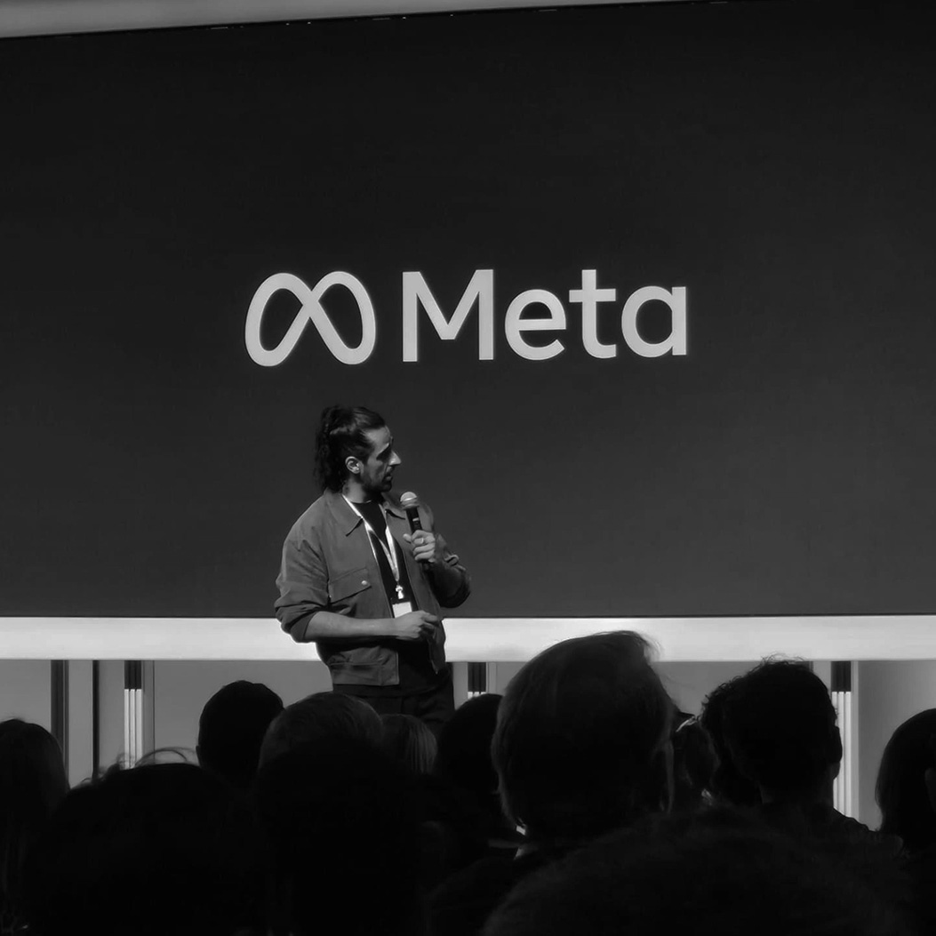 Eleniak's founder speaking at podium with microphone in front of Meta logo backdrop