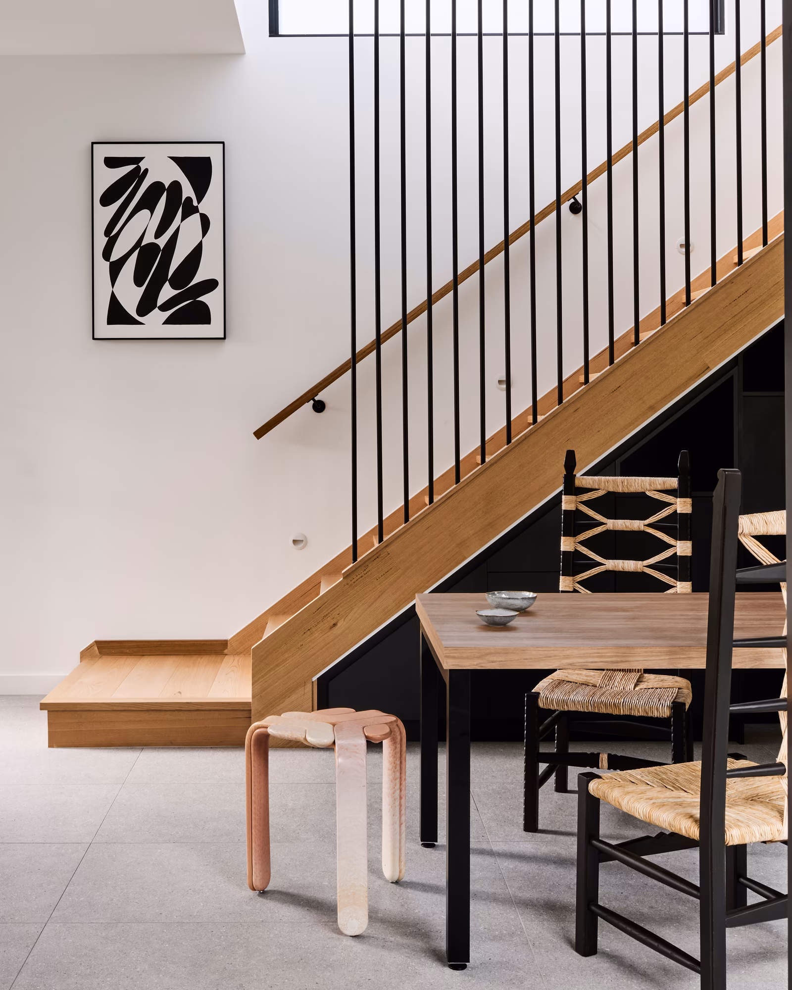 timber staircase with black steel balusters beside a dining table with rush-seat chairs, opus 4, thornbury
