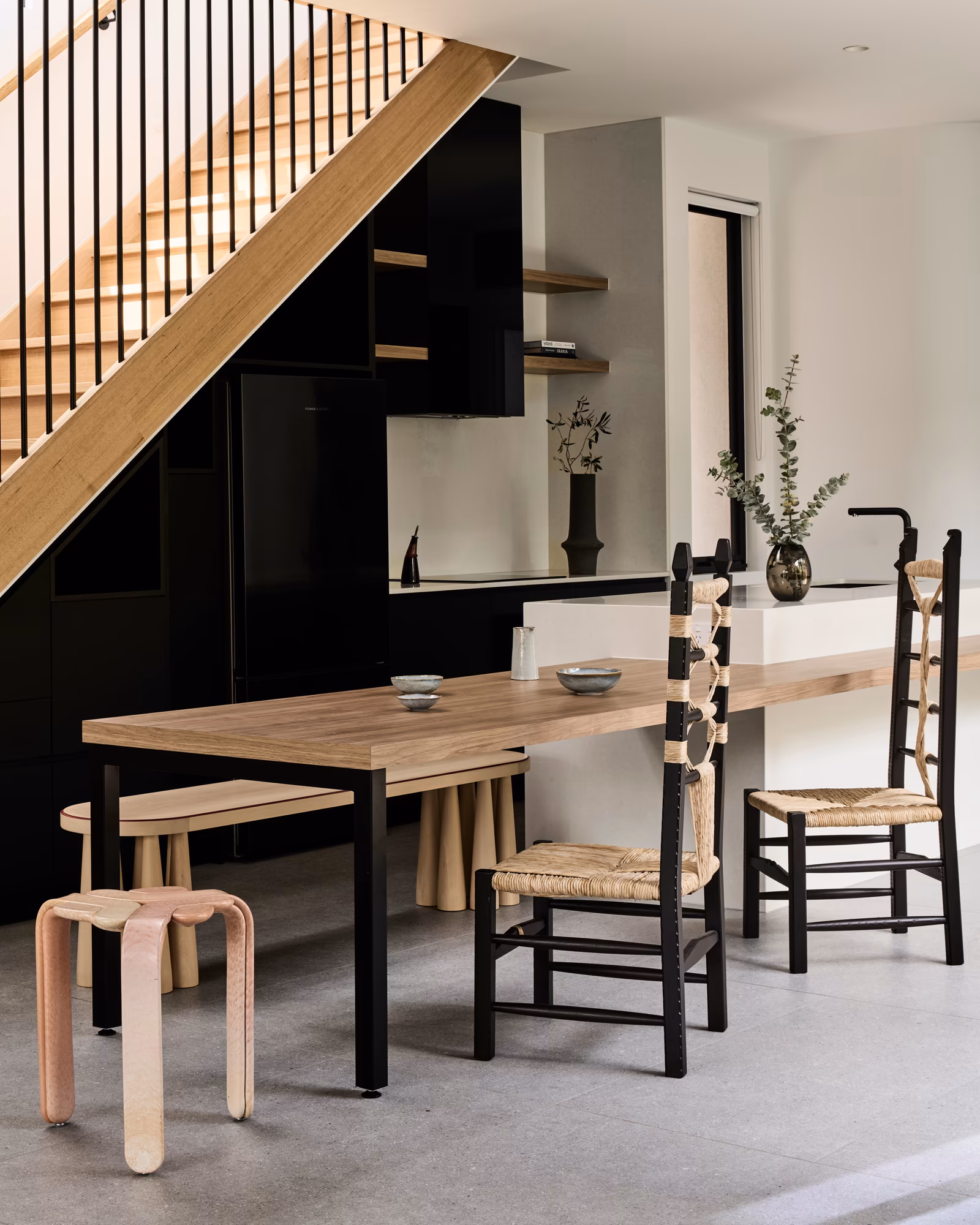 kitchen with black joinery and white island bench extending into a timber dining table, opus 4, thornbury