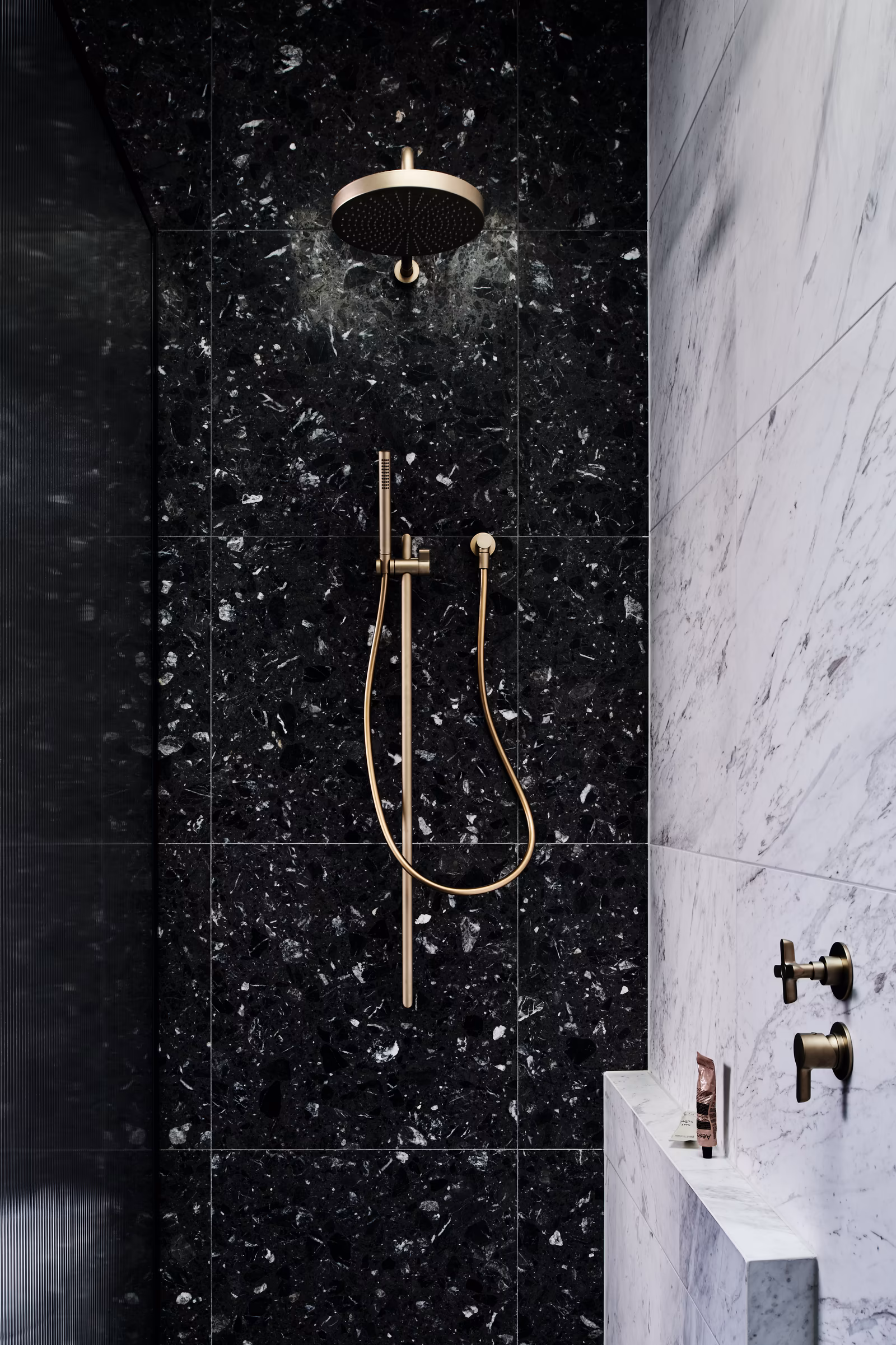 shower with black terrazzo-look tiles, white veined stone niche and brushed brass fittings, opus 73, middle park
