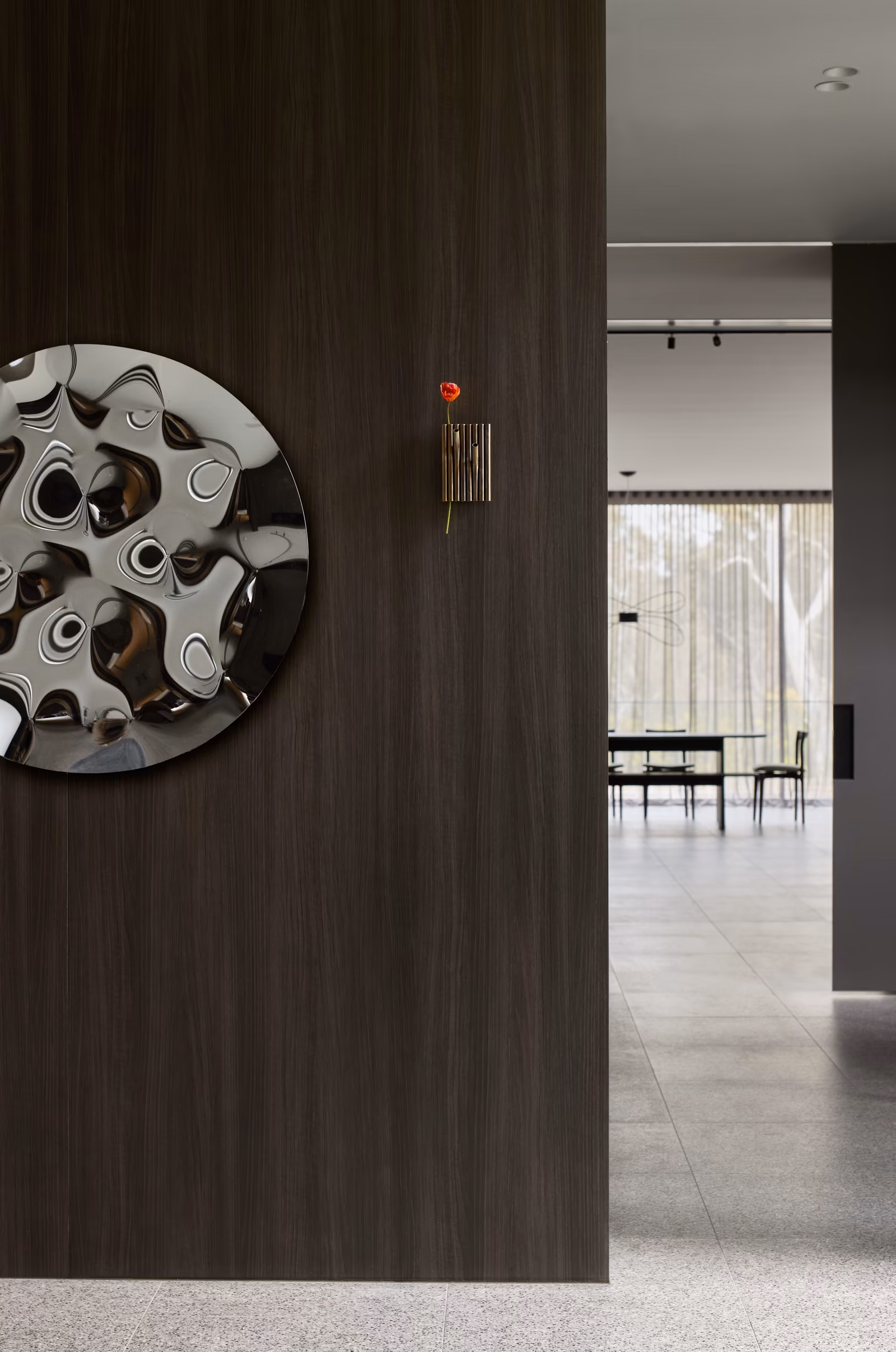 hallway with dark timber wall, round polished-metal artwork and view through to dining, opus 24, ashburton