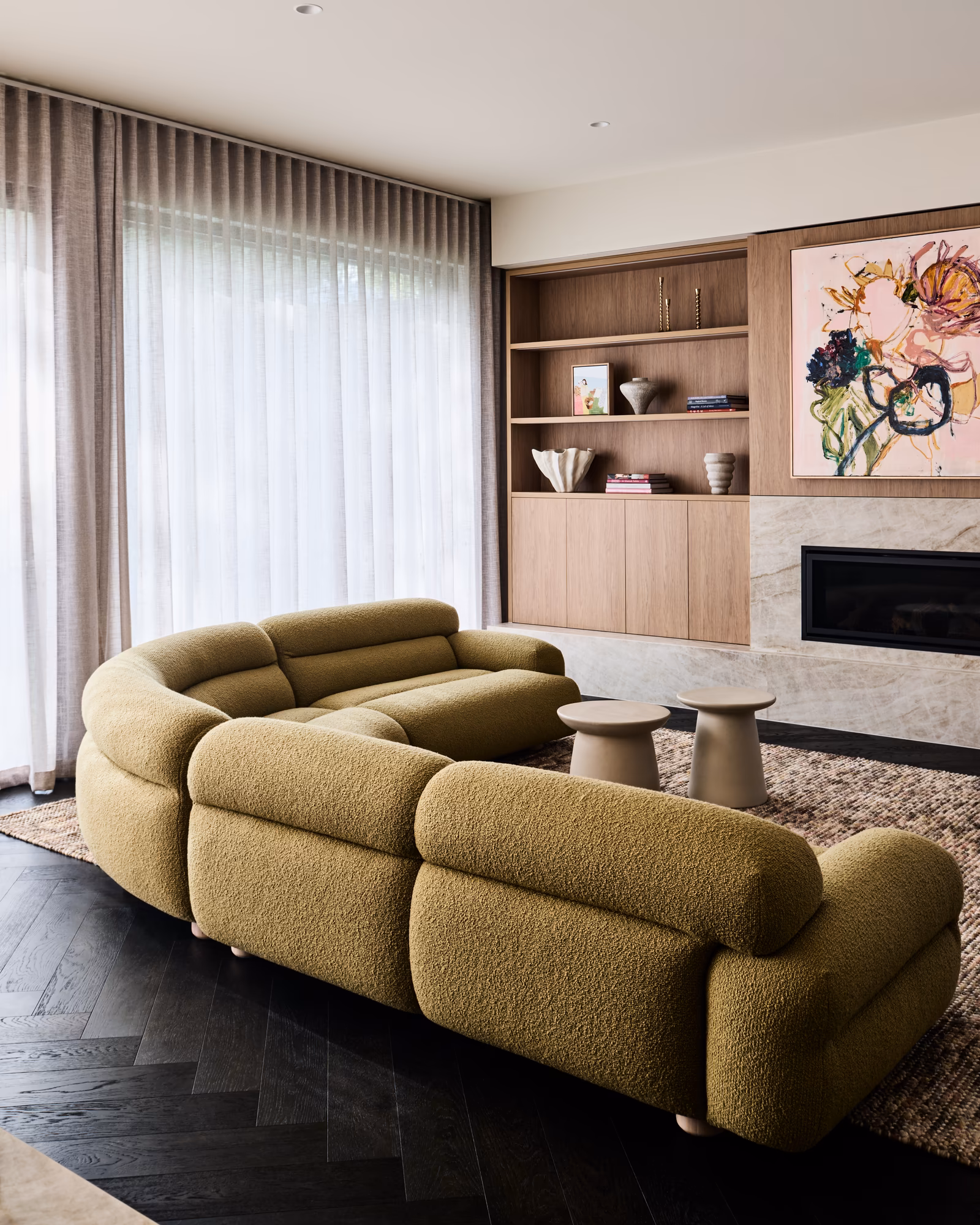 living room with curved olive boucle sofa facing a stone fireplace and timber shelving, opus 5, caulfield north