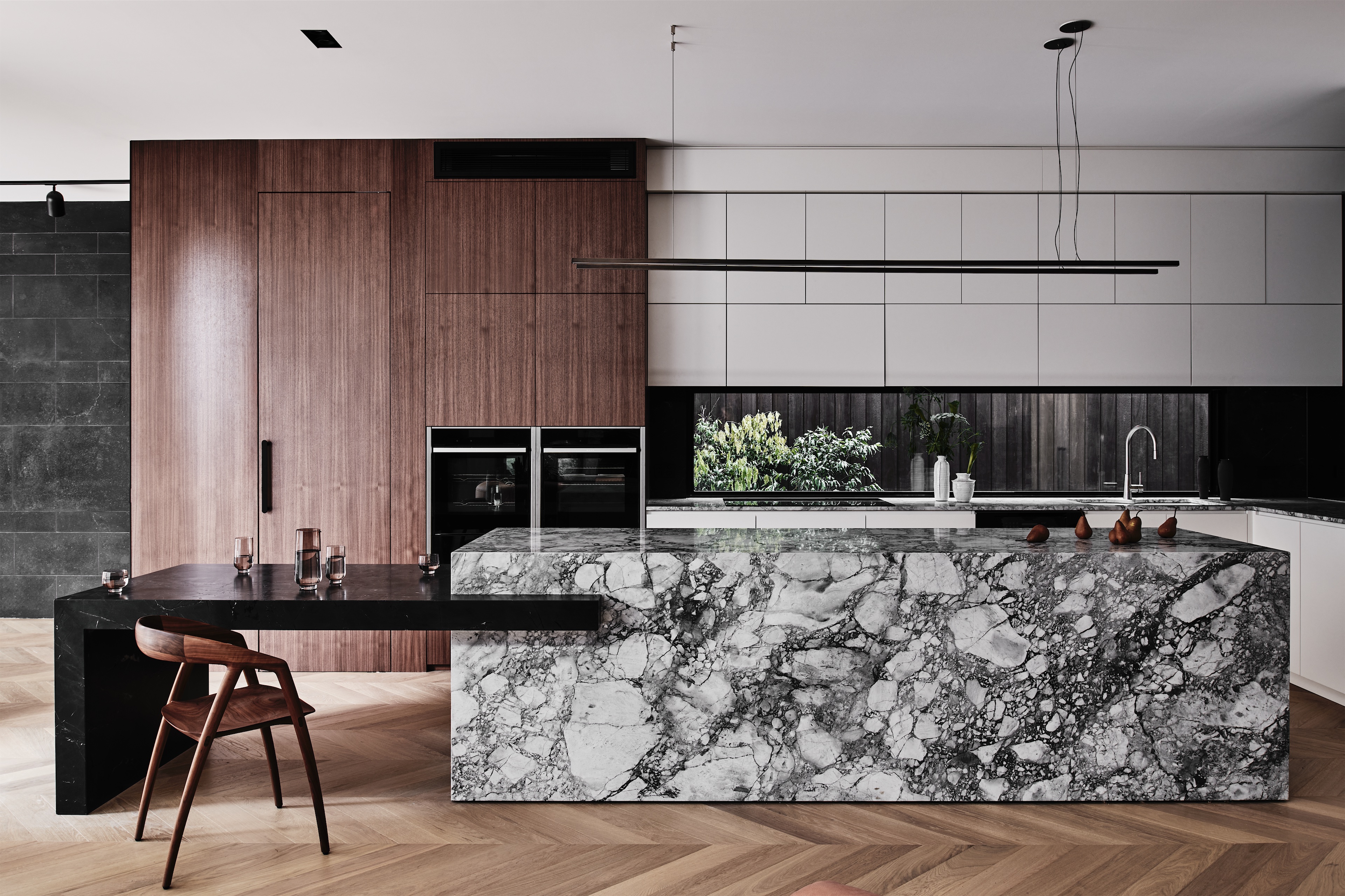 kitchen with veined stone island, walnut-toned joinery and black stone bench, opus 73, middle park