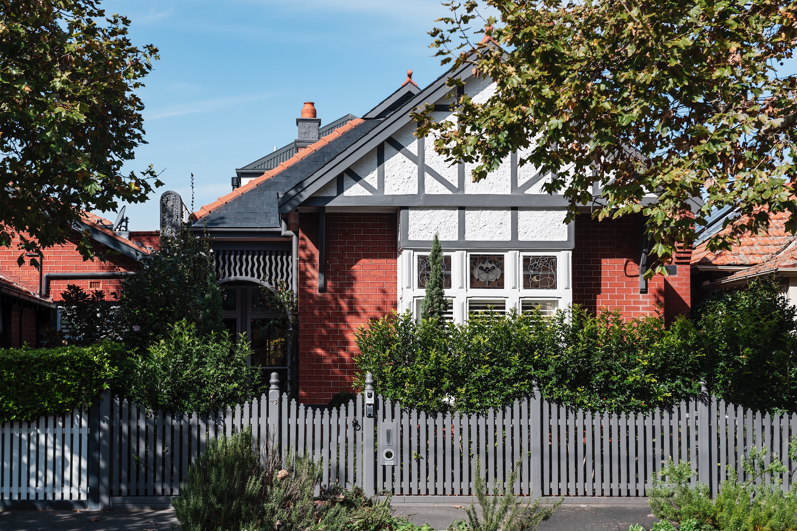 period red brick house with half-timbered gable, leadlight windows and grey picket fence, opus 73, middle park