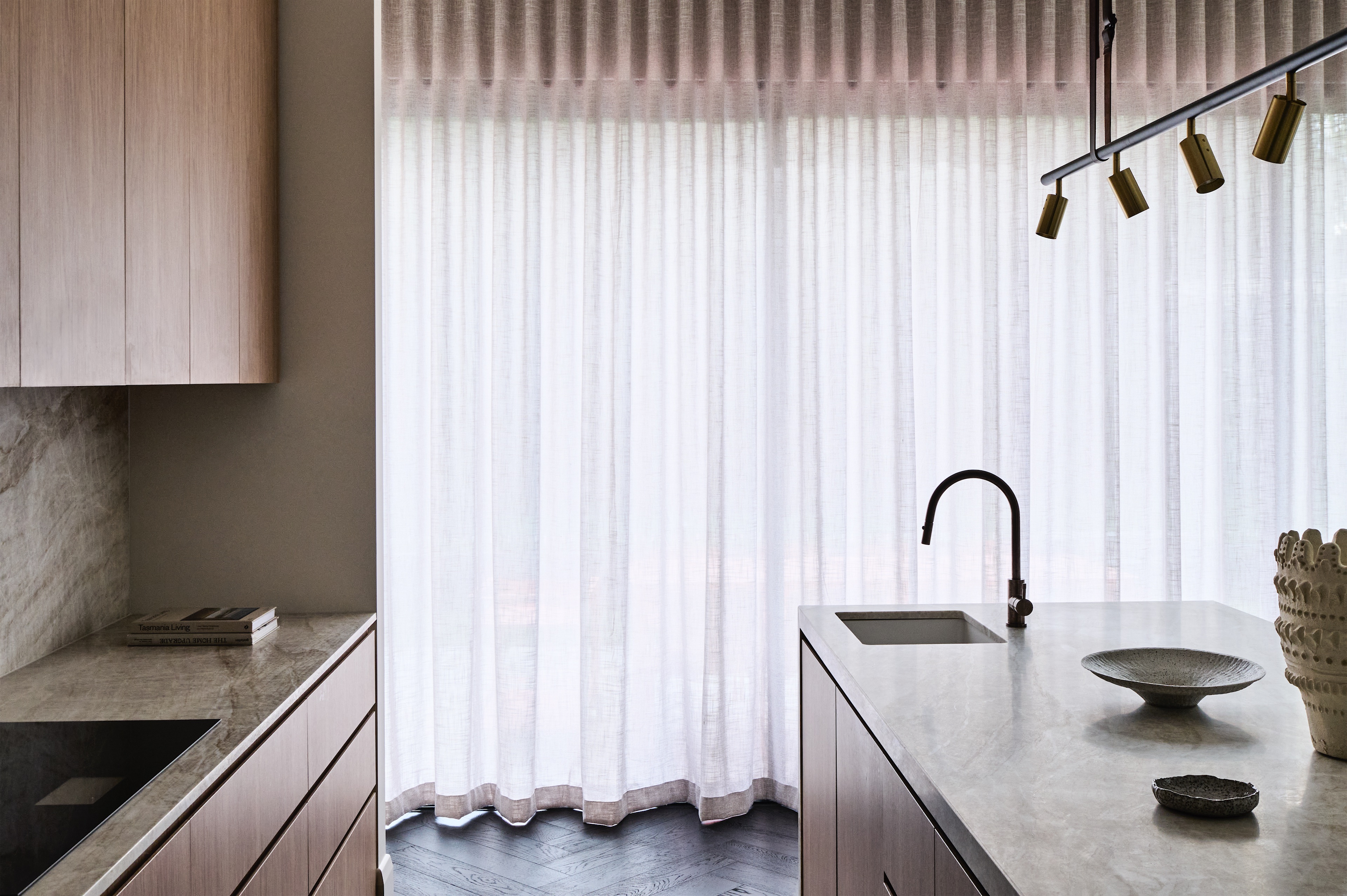 kitchen island sink in veined stone with timber cabinetry and sheer curtains, opus 5, caulfield north