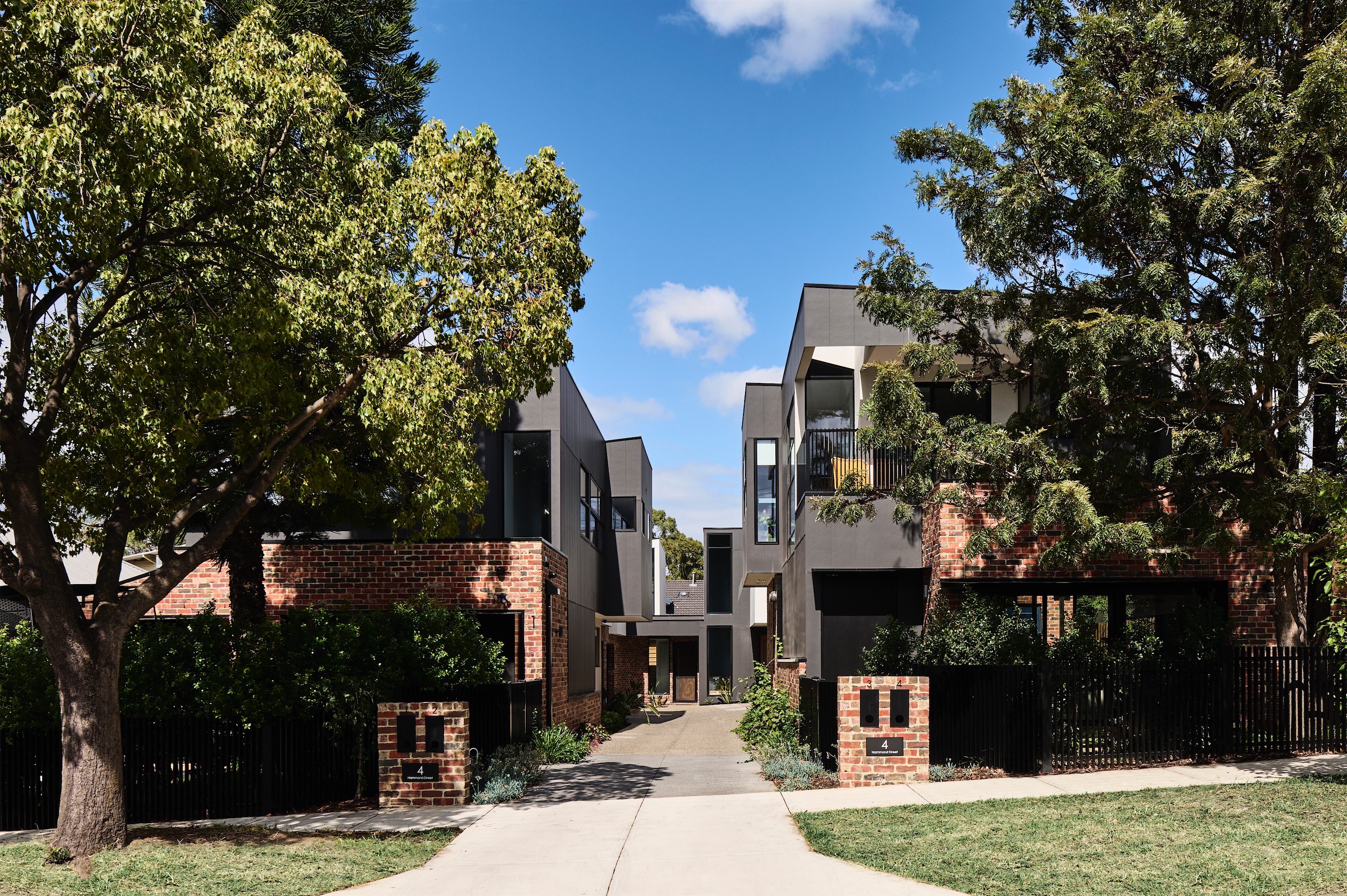 shared driveway between brick and black-clad townhouses with brick letterbox pillars, opus 4, thornbury