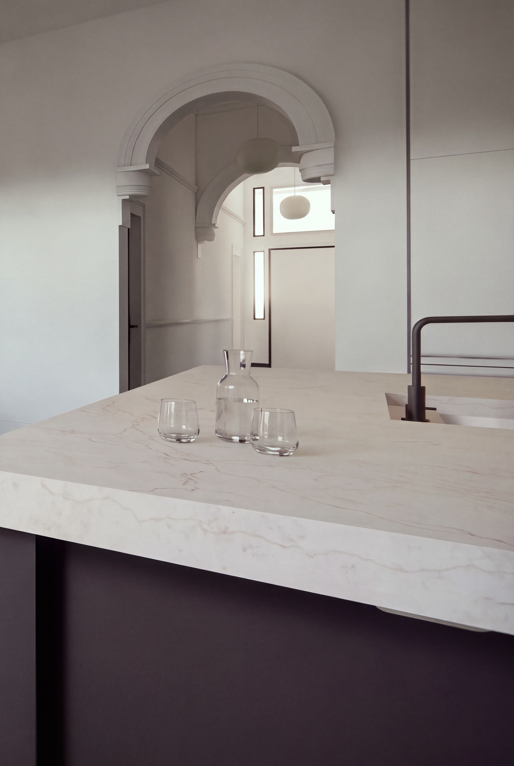 render of a pale stone kitchen bench with a dark tap, looking through a plaster arch to the hall, opus 11, malvern
