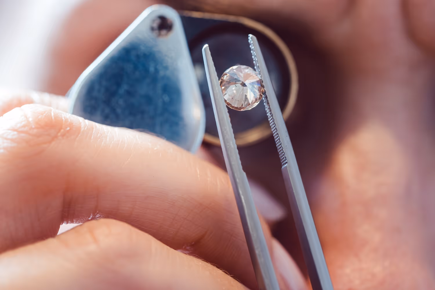 Inspecting a diamond through a jeweler’s loupe while it is held with tweezers