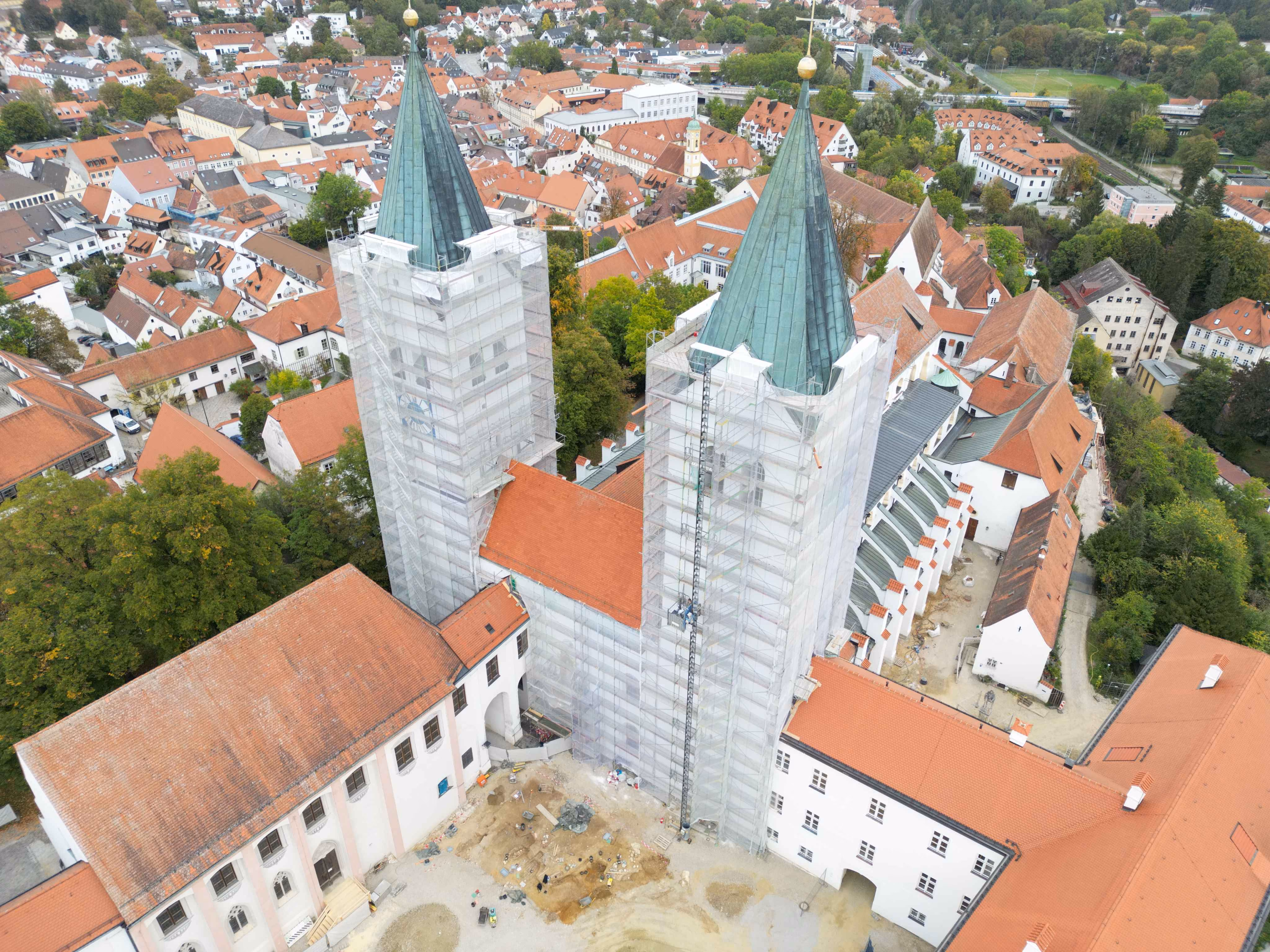 Luftaufnahme des Doms St. Maria und St. Korbinian mit eingerüsteten Türmen in einer Stadt.