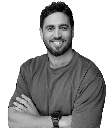 Smiling man with beard and curly hair wearing a plain t-shirt, arms crossed, and a wristwatch.