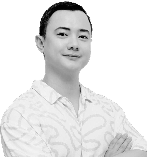 Portrait of a confident man with short dark hair wearing a patterned shirt, arms crossed.