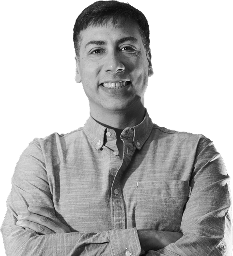 Man with arms crossed smiling, wearing a button-up shirt.