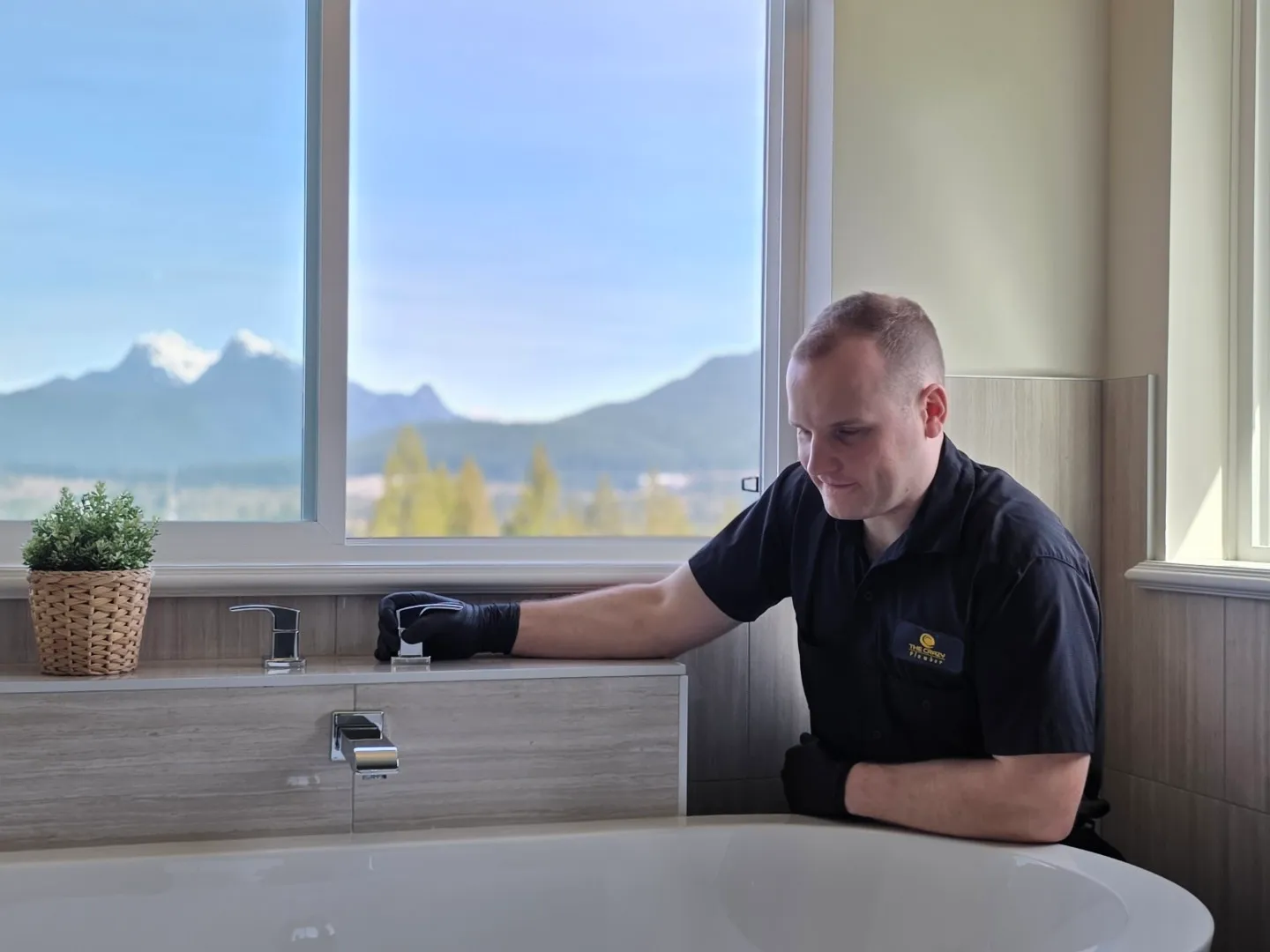 The Crazy Plumber technician inspecting the plumbing connections beneath a luxury freestanding bathtub