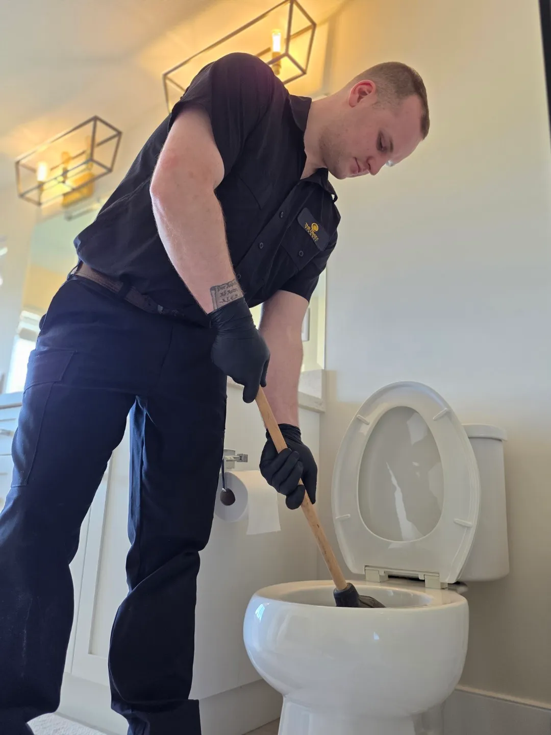 The Crazy Plumber technician using a plunger to clear a blocked toilet in a residential bathroom in the Lower Mainland